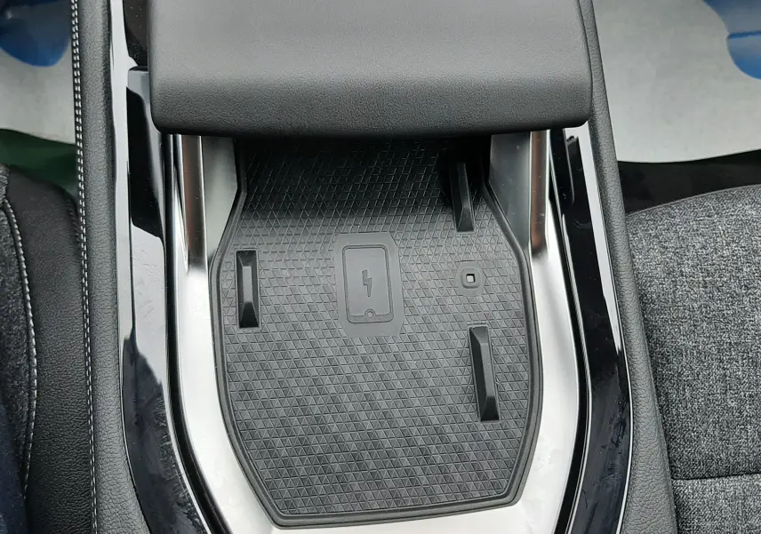 Gros plan sur la console centrale avec zone de charge sans fil du Renault Austral Ph.2 gris schiste, intérieur tissu gris.