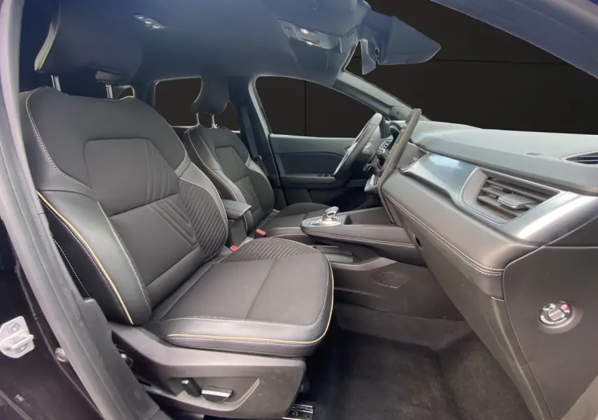 Vue intérieure côté gauche de la Renault Symbioz 2025, sièges tissu noir étoile avec surpiqûres claires et tableau de bord moderne.