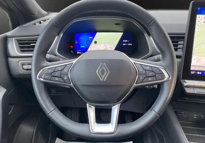 Vue intérieure centrée sur le volant noir perforé de la Renault Symbioz 2025 avec tableau de bord digital et écran tactile.
