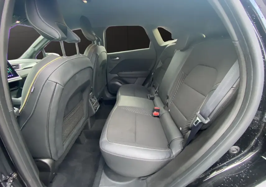 Vue intérieure arrière droite de la Renault Symbioz 2025 noire étoile, sièges en tissu noir avec surpiqûres contrastées.