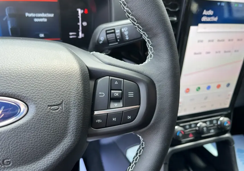Vue rapprochée du volant cuir multifonctions noir du Ford Ranger 2026 avec écran tactile et commandes au volant visibles.