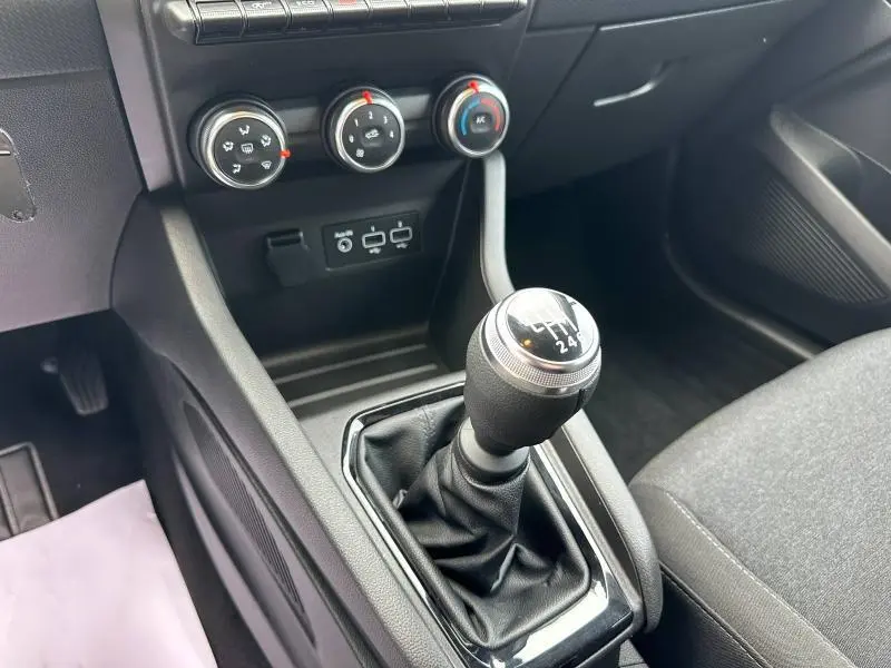 Gros plan sur le levier de vitesse manuel et la console centrale noire du Renault Clio Gris Schiste 2023, avec commandes de climatisation.