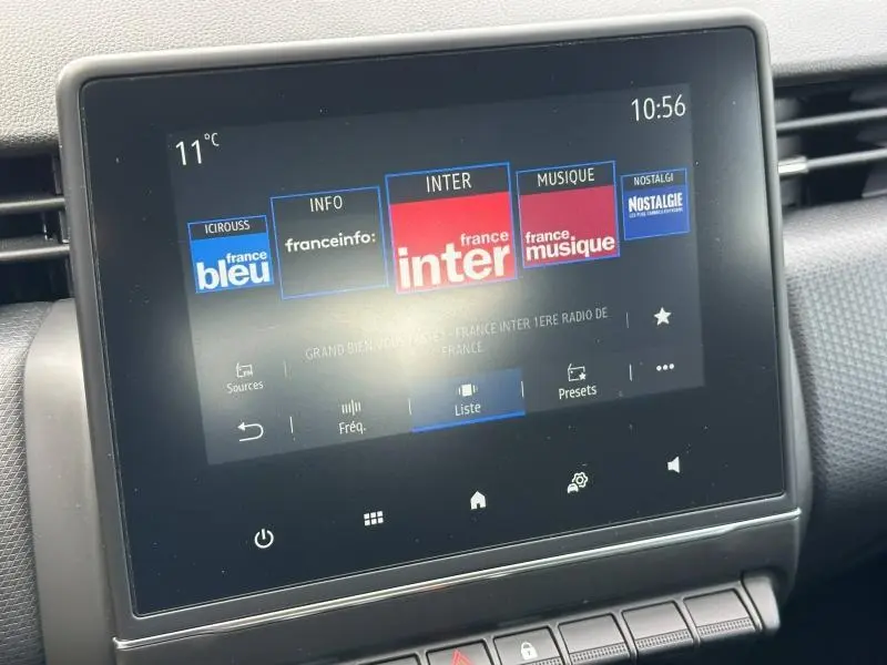 Écran tactile central de la Renault Clio 2023 affichant les stations radio, avec tableau de bord gris et commandes en dessous.