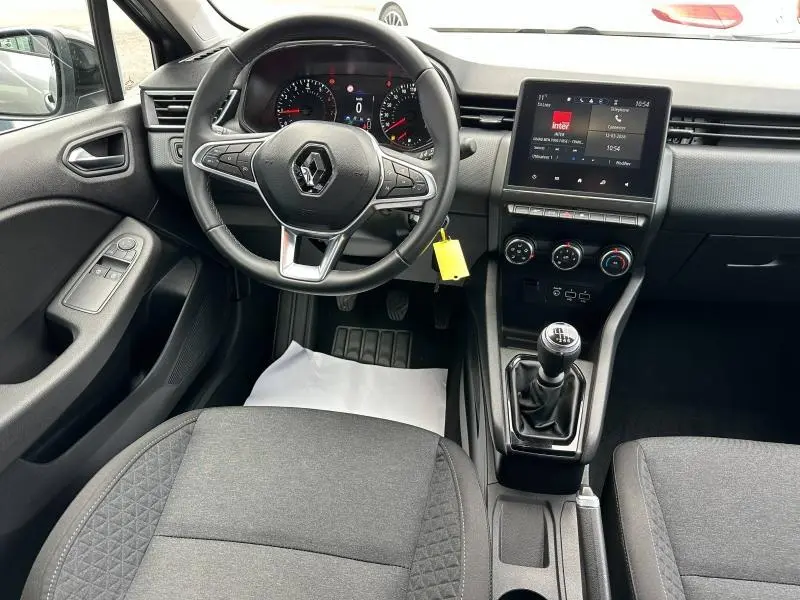 Vue intérieure avant de la Renault Clio 1.0 TCe 90ch gris schiste 2023, volant multifonction et boîte manuelle visible.