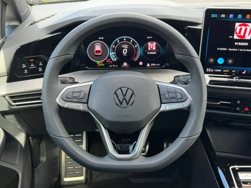 Vue intérieure centrée sur le volant cuir multifonction de la Volkswagen Golf gris lunaire avec tableau de bord numérique.
