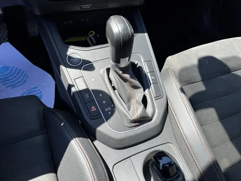 Gros plan sur la console centrale de la SEAT Ibiza 1.5 TSI 150 cv FR Xclusive 2022, boîte auto avec levier de vitesses et coutures orange.