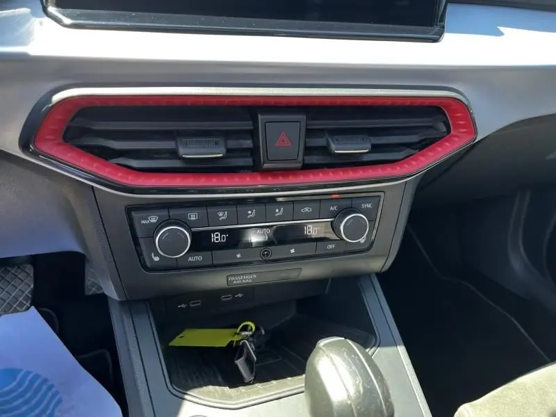 Vue rapprochée de la console centrale de la SEAT Ibiza 2022 bleu foncé, avec aérateurs rouges et commandes climatisation digitales.