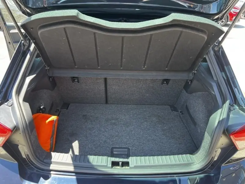 Coffre ouvert vu de l'arrière d'une SEAT Ibiza bleu foncé métal 2022, avec un sac orange visible à gauche.