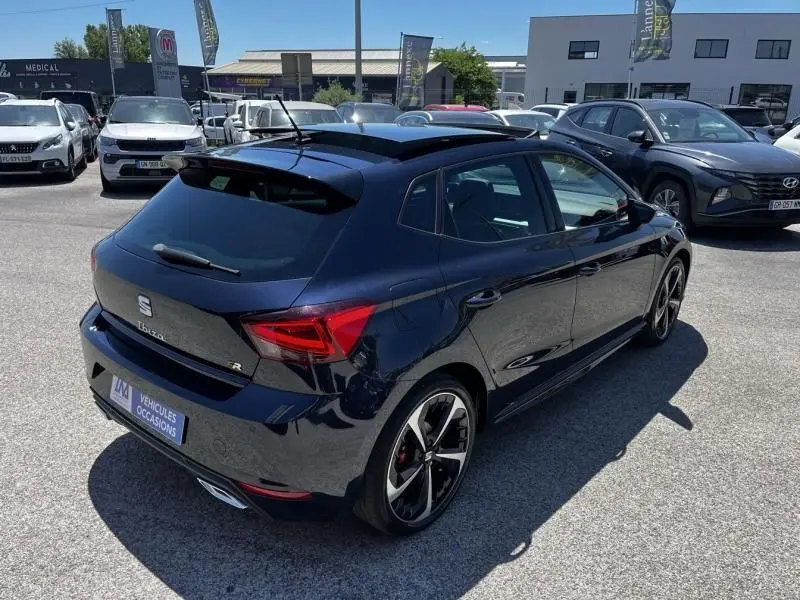 Vue 3/4 arrière droite d'une SEAT Ibiza 2022 bleu foncé métal avec jantes alliage et toit ouvrant panoramique.