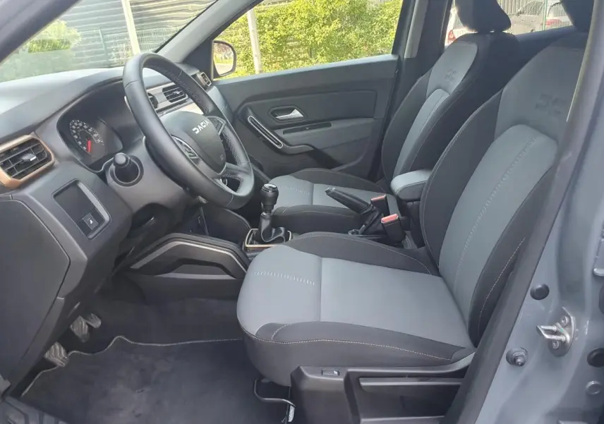 Vue intérieure côté conducteur du Dacia Duster 1.5 DCI 115 Extreme 4x4 gris urbain, sièges bi-ton et volant multifonction.