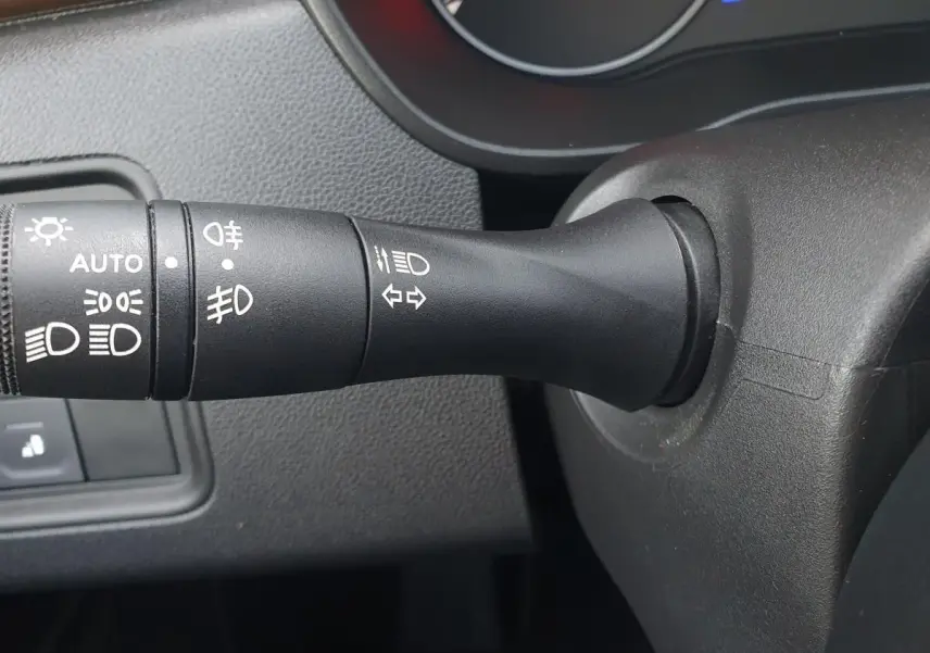 Gros plan sur la commande des feux et clignotants à gauche du volant dans l'habitacle du Dacia Duster 2023.