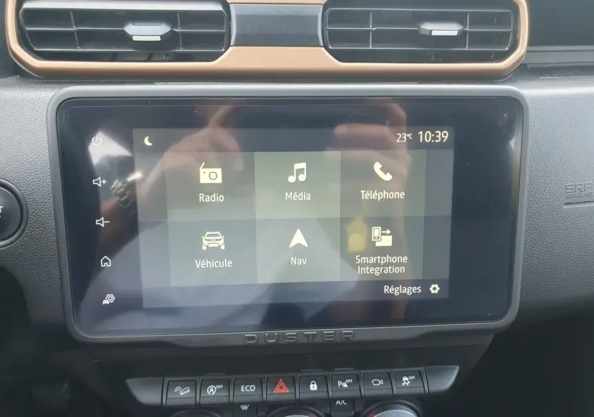 Écran tactile central du Dacia Duster 2023 avec interface multimédia et commandes sous l'écran, vue intérieure frontale.