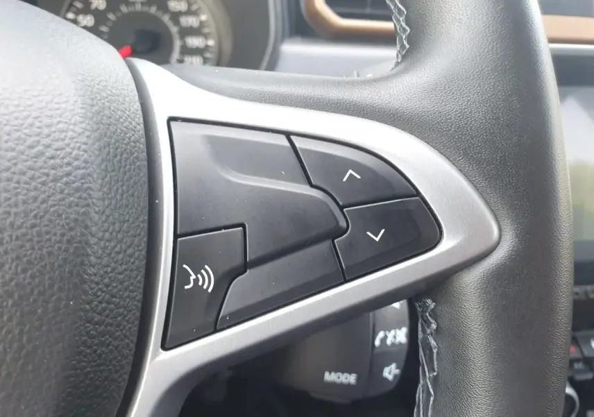 Gros plan sur les commandes du volant noir du Dacia Duster 2023, avec boutons de réglage et commande vocale.