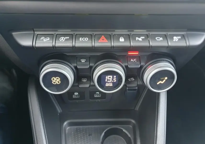Vue rapprochée du tableau de bord du Dacia Duster 2023, montrant les commandes de climatisation automatique et les boutons de fonction.