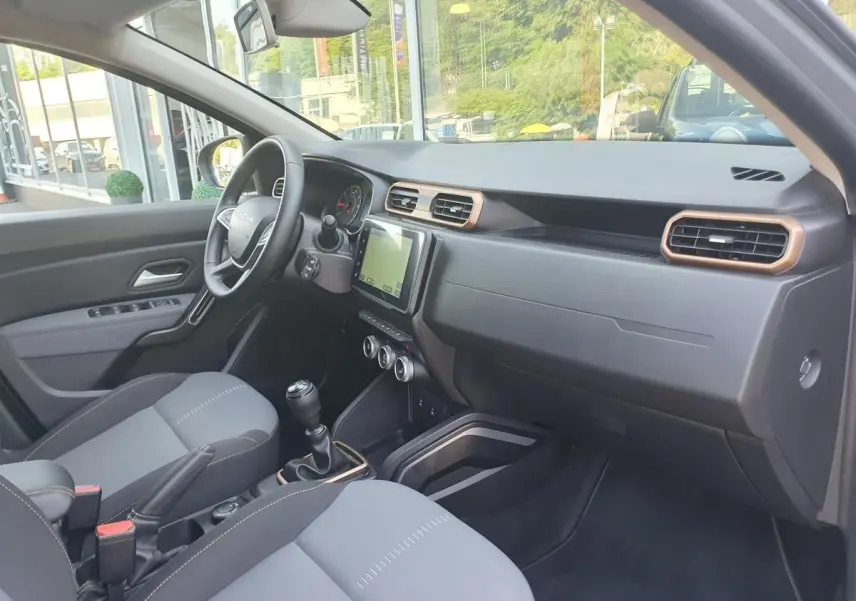 Intérieur du Dacia Duster 2023 gris urbain, vue côté conducteur avec tableau de bord et écran tactile central.