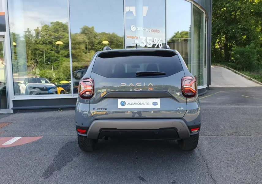 Vue arrière d'un Dacia Duster gris urbain 2023 avec logo DACIA et badge 4x4 visible sur un parking.