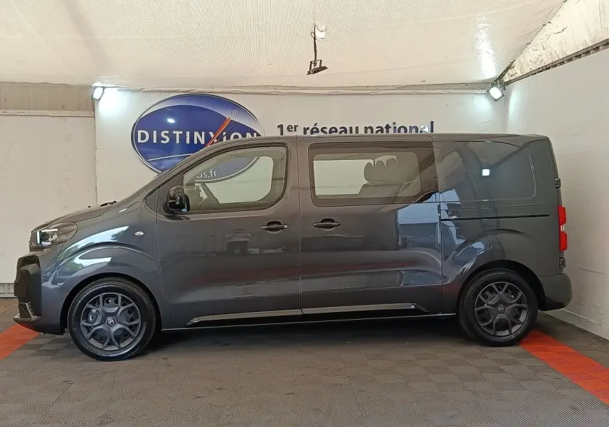 Vue de profil côté gauche d'un Citroën Jumpy gris foncé 2025 avec vitres arrière teintées et jantes spécifiques.
