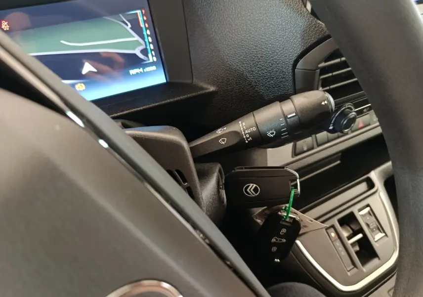 Vue intérieure rapprochée du volant noir d’un Citroën Jumpy 2025 avec clé insérée et écran de navigation allumé.