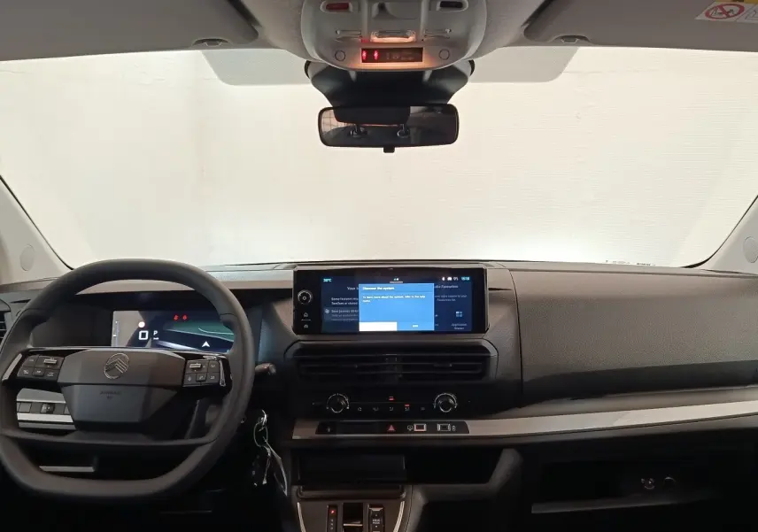 Vue frontale de l'habitacle gris foncé du Citroën Jumpy 2025, avec volant multifonctions et écran tactile central allumé.