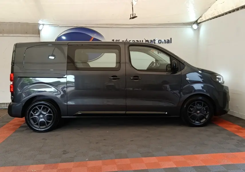Vue de profil côté droit d'un Citroën Jumpy gris foncé 2025 avec vitres latérales et jantes noires distinctives.