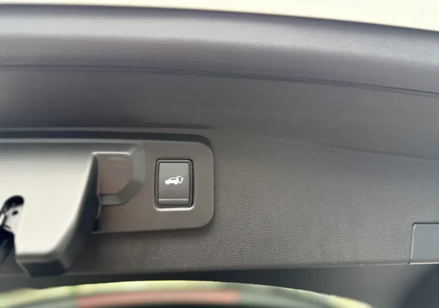 Bouton d'ouverture électrique du hayon sur la partie intérieure du coffre du Renault Austral blanc nacré.
