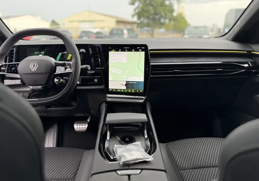 Vue intérieure avant du Renault Austral Esprit Alpine avec tableau de bord noir, écran tactile vertical et volant multifonction.