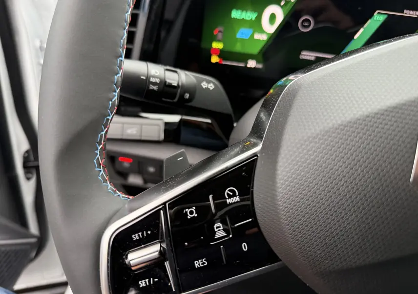 Gros plan sur le volant avec commandes intégrées et tableau de bord numérique allumé du Renault Austral blanc nacré.