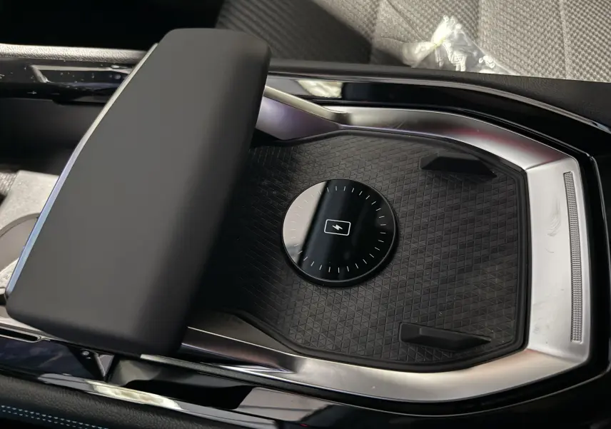 Vue rapprochée de la console centrale noire du Renault Austral Esprit Alpine, avec un espace de recharge sans fil et accoudoir rembourré.