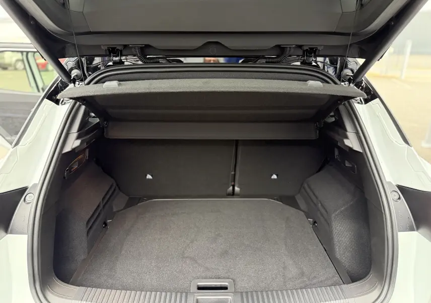 Vue arrière du coffre ouvert du Renault Austral blanc nacré avec toit noir, montrant un espace de chargement spacieux et propre.