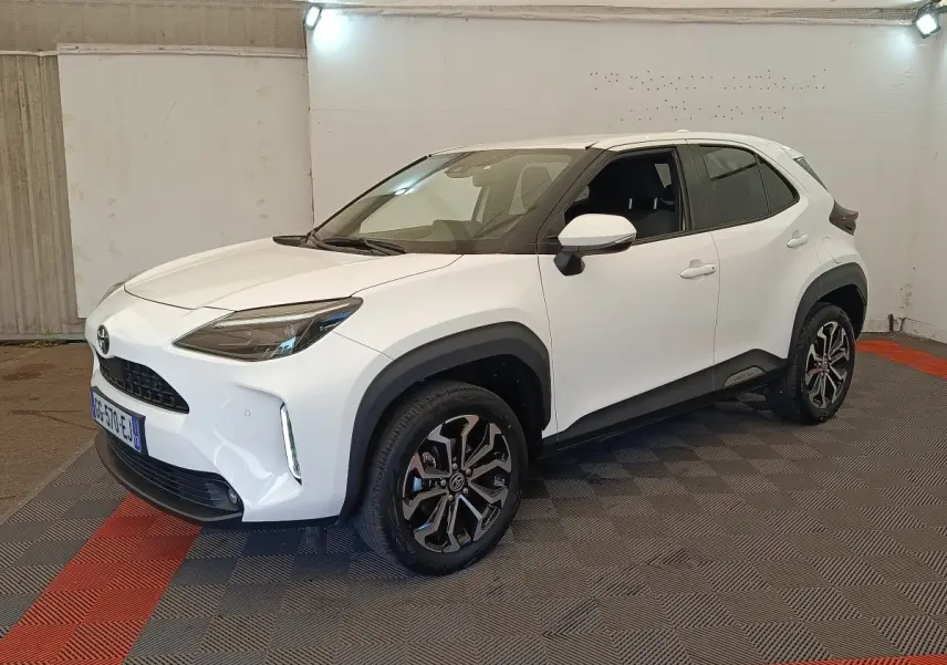 Toyota Yaris Cross blanc vue 3/4 avant droit, avec jantes alliage noires et protections plastiques noires.