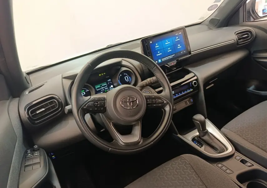 Vue intérieure côté conducteur du Toyota Yaris Cross 1.5 Hybrid 2022, volant cuir et écran tactile central.