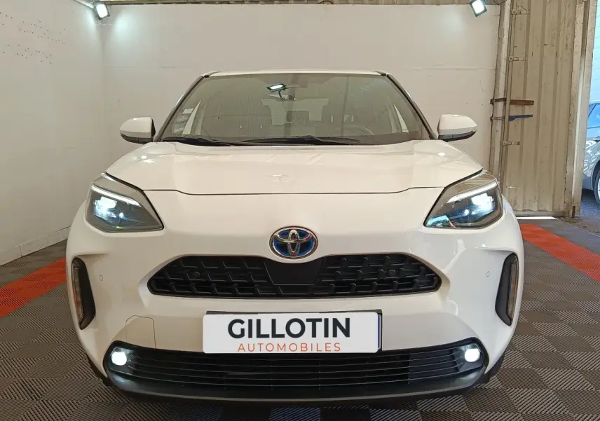 Vue de face du Toyota Yaris Cross blanc avec phares LED allumés et calandre noire distinctive.
