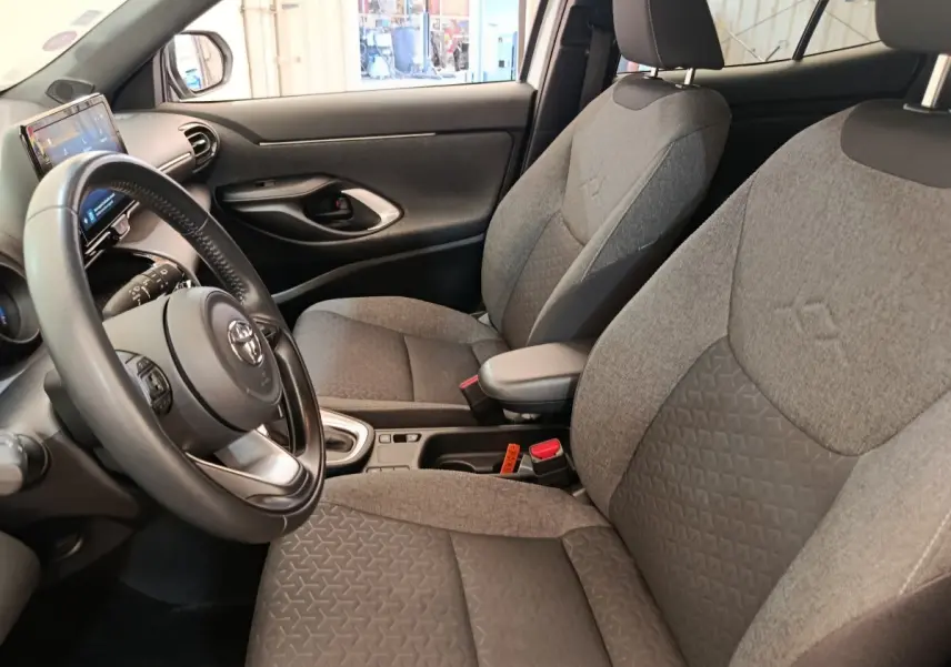 Vue intérieure côté conducteur de la Toyota Yaris Cross 1.5 Hybrid 116h, sièges gris et volant cuir multifonctions.