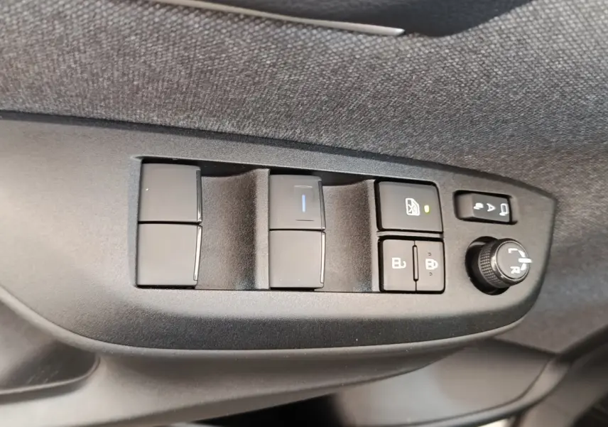 Gros plan sur les commandes de porte côté conducteur de la Toyota Yaris Cross blanche, avec boutons de vitres et réglage rétroviseurs.
