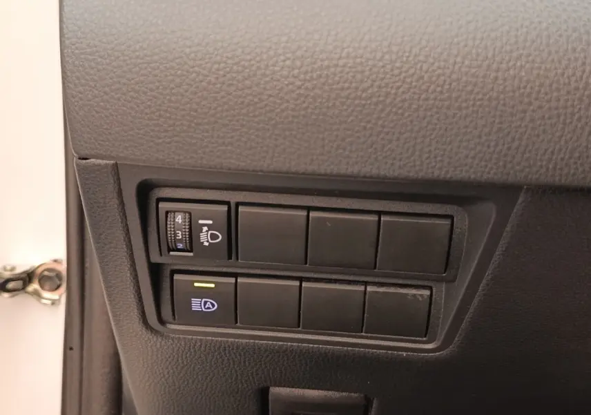 Gros plan sur les commandes d’éclairage côté gauche d’une Toyota Yaris Cross blanche, intérieur noir.