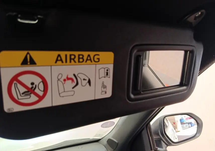 Détail intérieur du pare-soleil côté conducteur avec miroir et avertissement airbag dans une Toyota Yaris Cross blanche.