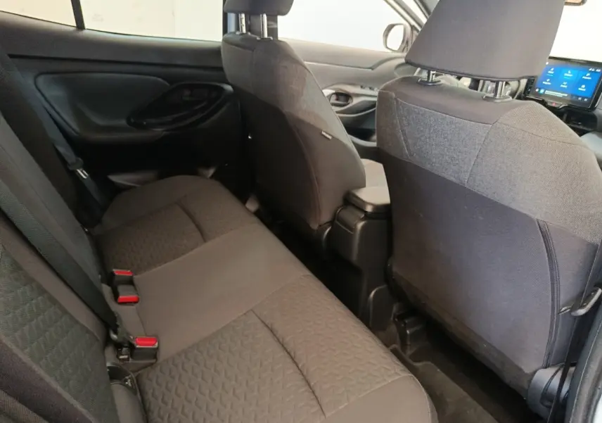 Vue intérieure arrière de la Toyota Yaris Cross 2022, sièges tissu gris foncé et tableau de bord avec écran tactile visible.