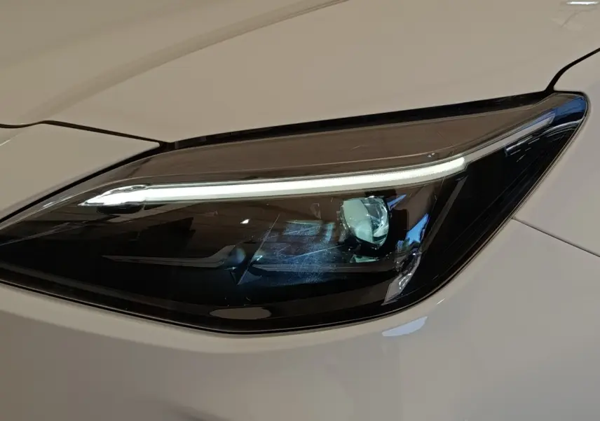 Gros plan sur le phare avant droit LED du Toyota Yaris Cross blanc, soulignant son design moderne et épuré.