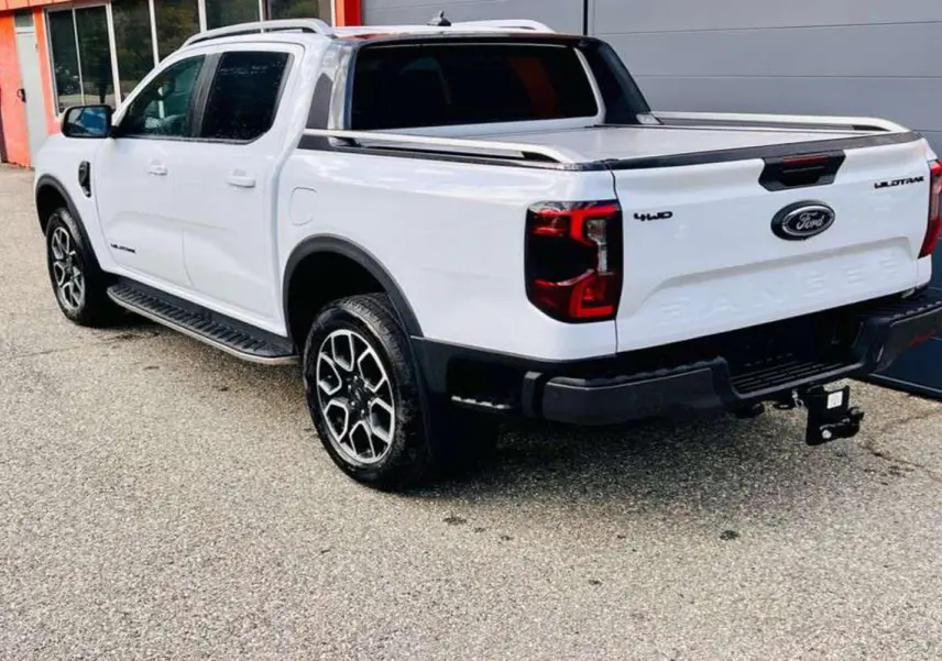 Ford Ranger Wildtrak blanc vu en 3/4 arrière droit, avec jantes alu 20 pouces et attelage visible.