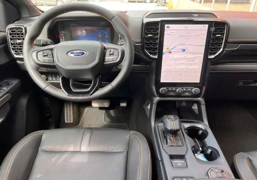 Vue intérieure du tableau de bord du Ford Ranger Wildtrak 2026, volant cuir noir et écran tactile central vertical.