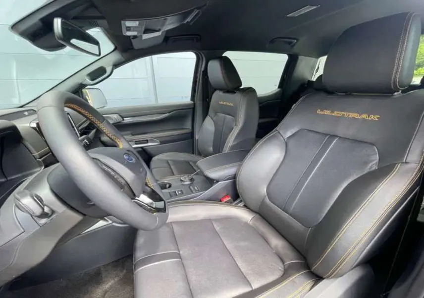 Vue intérieure côté conducteur du Ford Ranger Wildtrak 2026 avec sièges cuir noirs brodés et volant multifonctions.