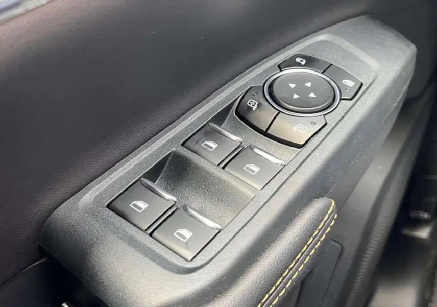 Gros plan sur les commandes de lève-vitres et réglage des rétroviseurs côté conducteur du Ford Ranger blanc 2026 Wildtrak Plus.