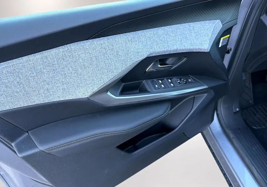 Vue rapprochée de la porte avant gauche gris artense du Peugeot 5008 Hybrid 145 allure avec commandes de vitres et rétroviseurs.