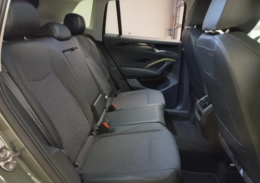 Vue intérieure arrière du Volkswagen Tiguan 2025, sièges tissu gris et cuir noir avec détails modernes sur la portière côté droit.