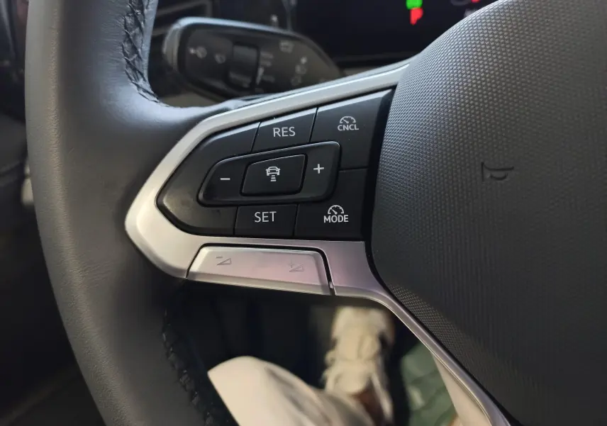 Gros plan sur les commandes de régulateur de vitesse au volant du Volkswagen Tiguan 2.0 TDI 150 DSG7 Vert Cipressino.