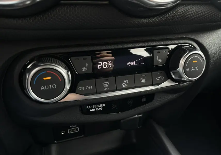 Gros plan sur la console centrale du Nissan Juke 2024, affichant la climatisation automatique et les sièges chauffants.