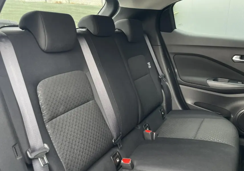 Vue latérale droite des sièges arrière noirs du Nissan Juke 2024, avec ceintures grises et tissu texturé.