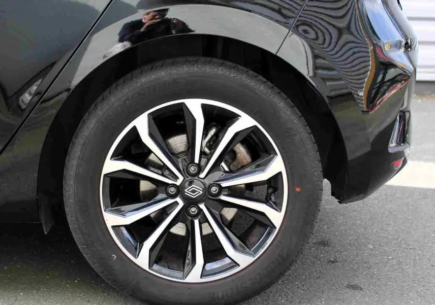 Gros plan sur la roue arrière droite d'une Renault Clio noire étoile métal avec jante alliage bicolore moderne.