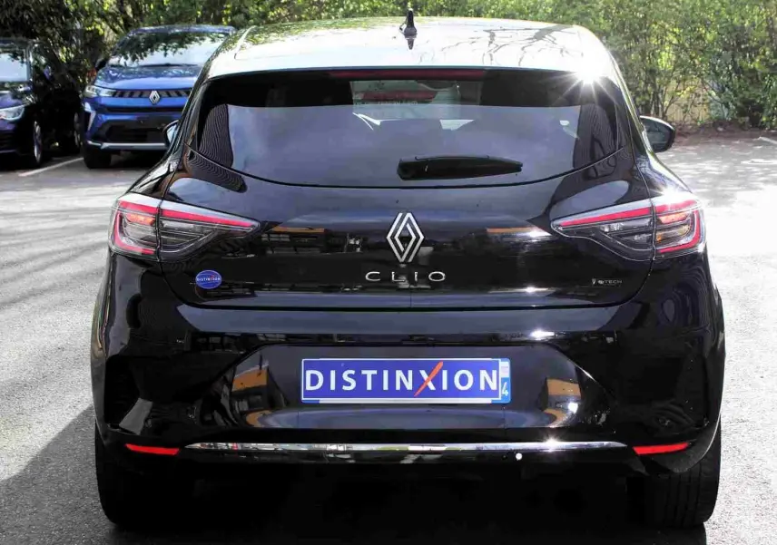 Vue arrière d'une Renault Clio noire étoile métal 2025 avec logo distinctif et plaque "DISTINXION" visible.