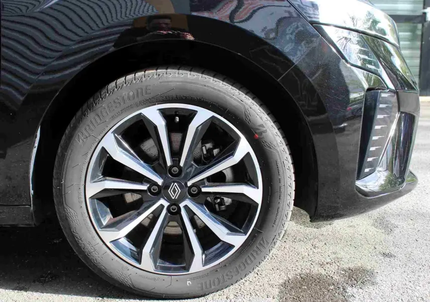 Gros plan sur la roue avant droite de la Renault Clio noire étoile métal, avec jante alliage au design moderne.